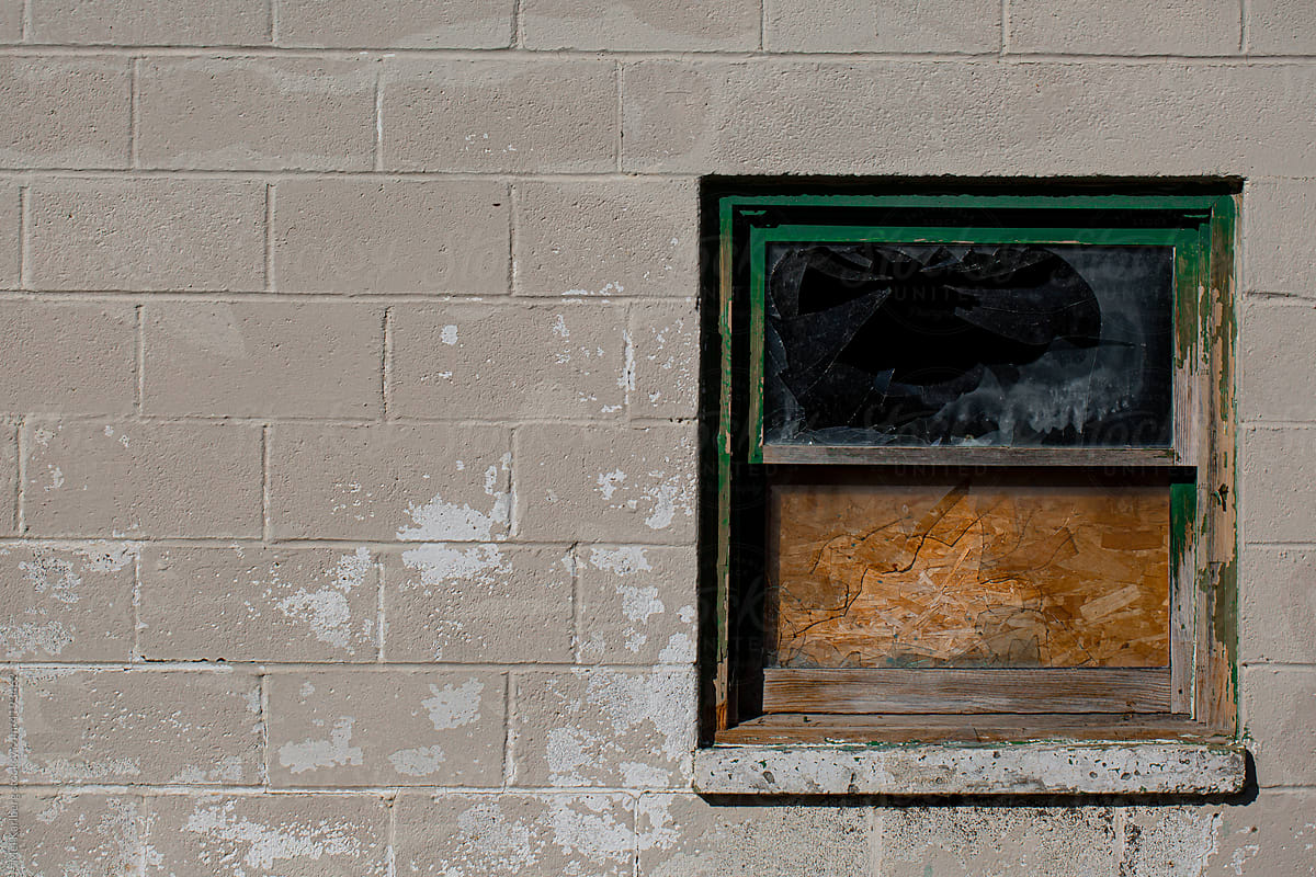 Broken window on a textured concrete block wall
