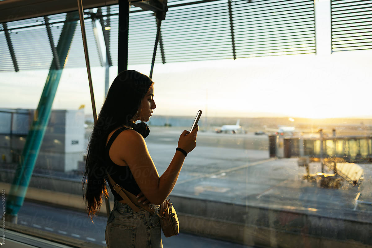 Female traveler using smartphone waiting at airport
