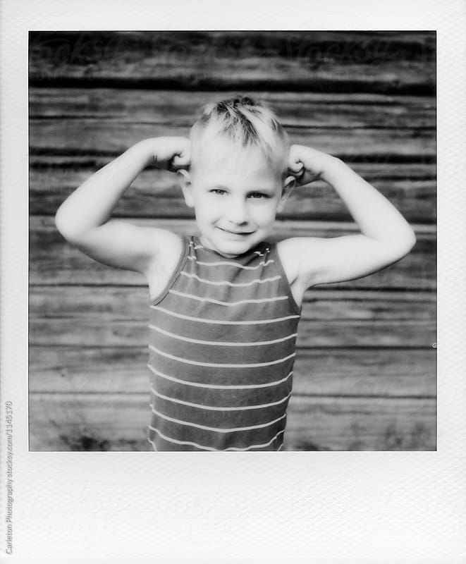 Instant black and white photo of five year old boy flexing