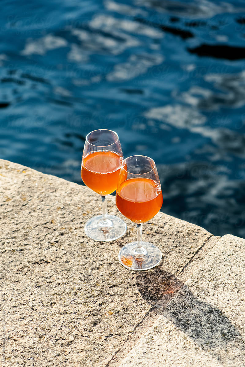 Close up of two glass cups with an orange wine on a concrete surface