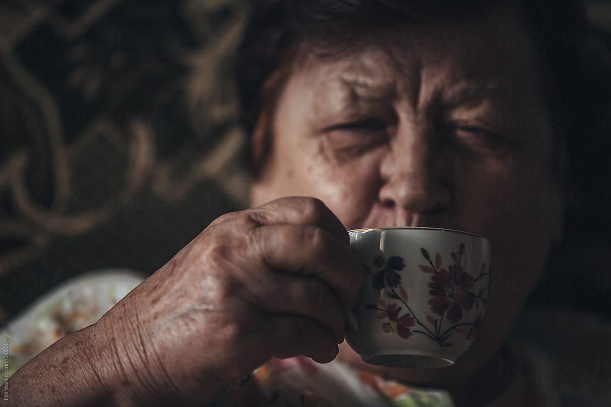 Old woman drinking tea at home portrait
