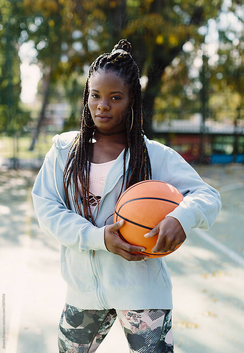 Young black woman with basketball ball looking at camera