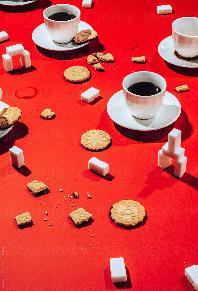 Coffee cups with biscuits and sugar on red .