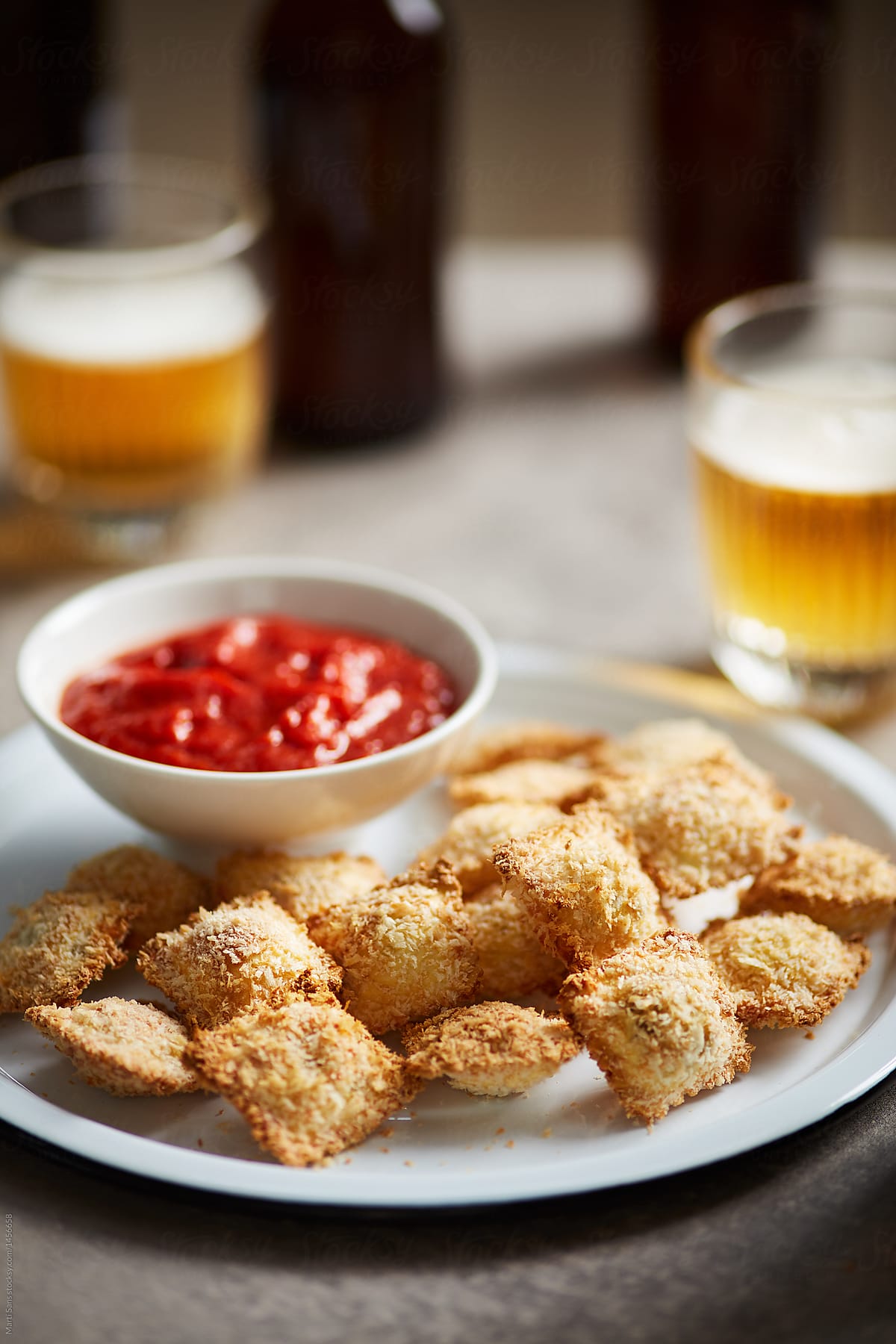 Homemade fried ravioli with sauce and beer.