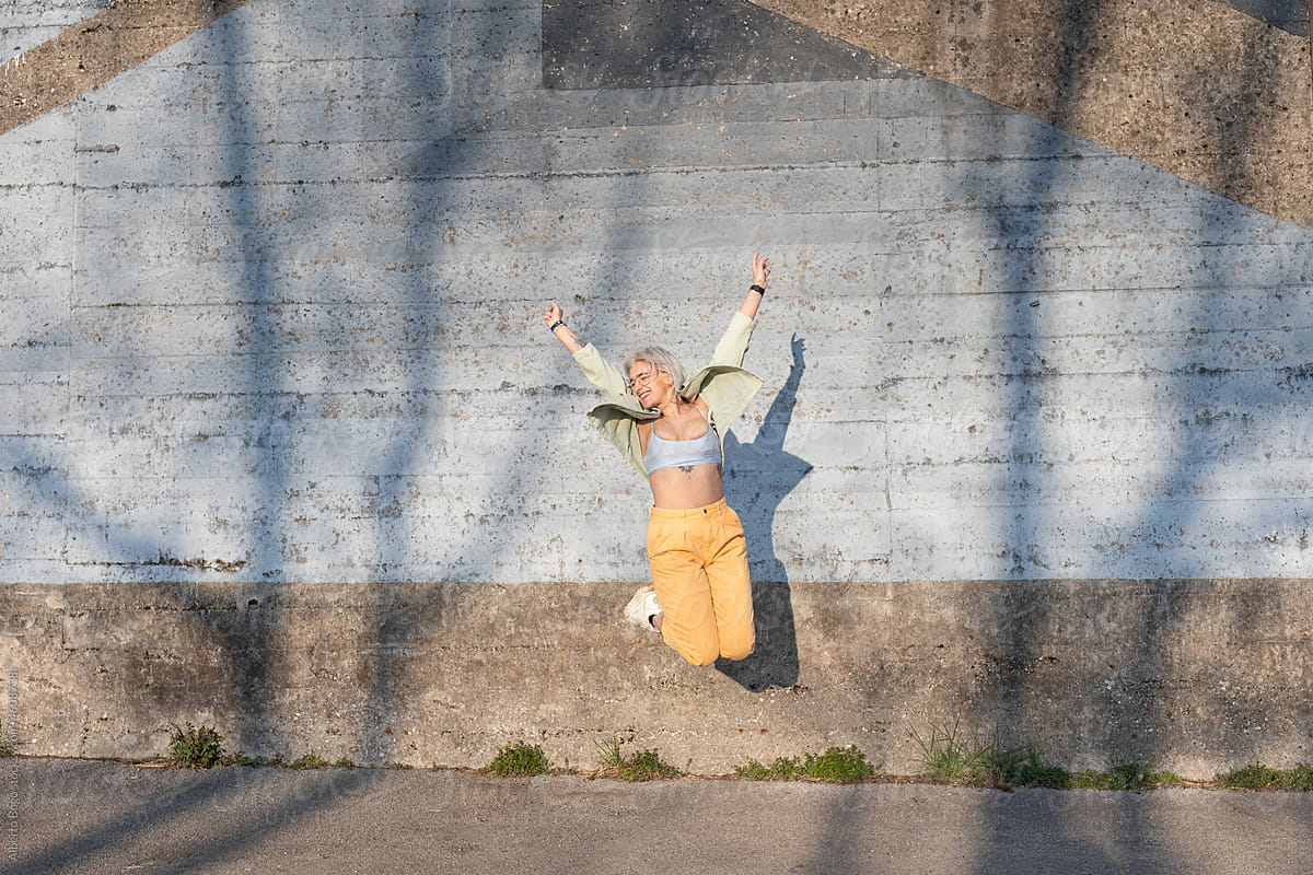 Young Woman Jumping In Front Of Concrete Wall