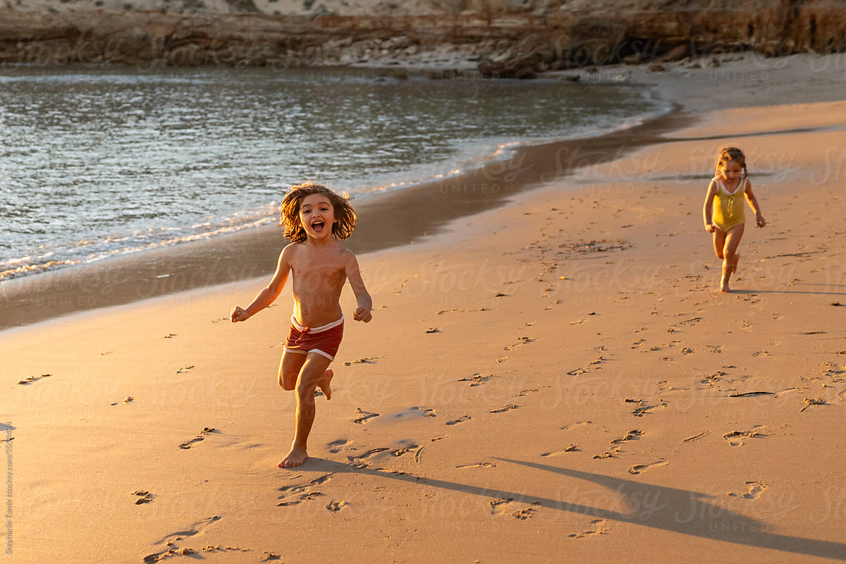 Children\'s running on the beach at sunset.