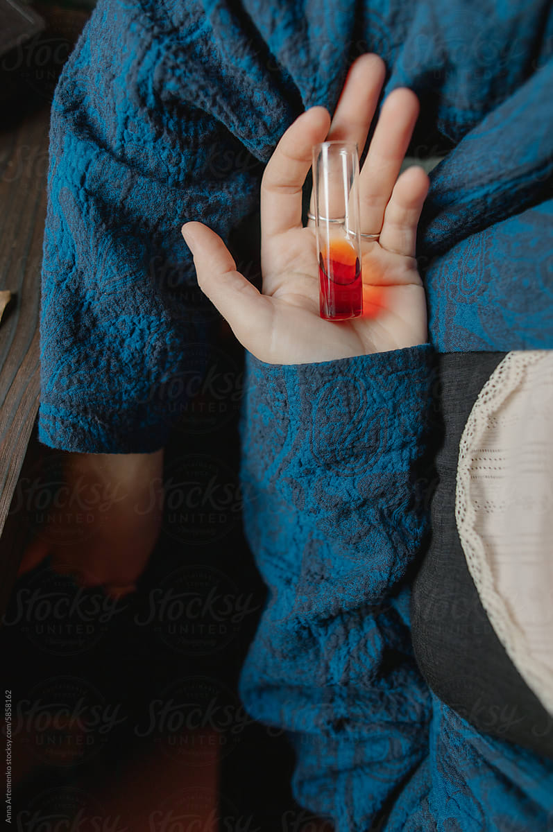 test tube of red perfume in hand