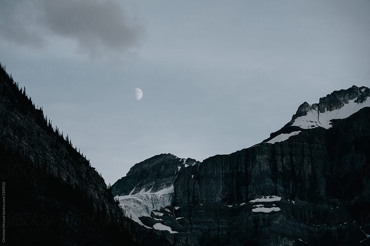 the moon rising over the rocky mountains