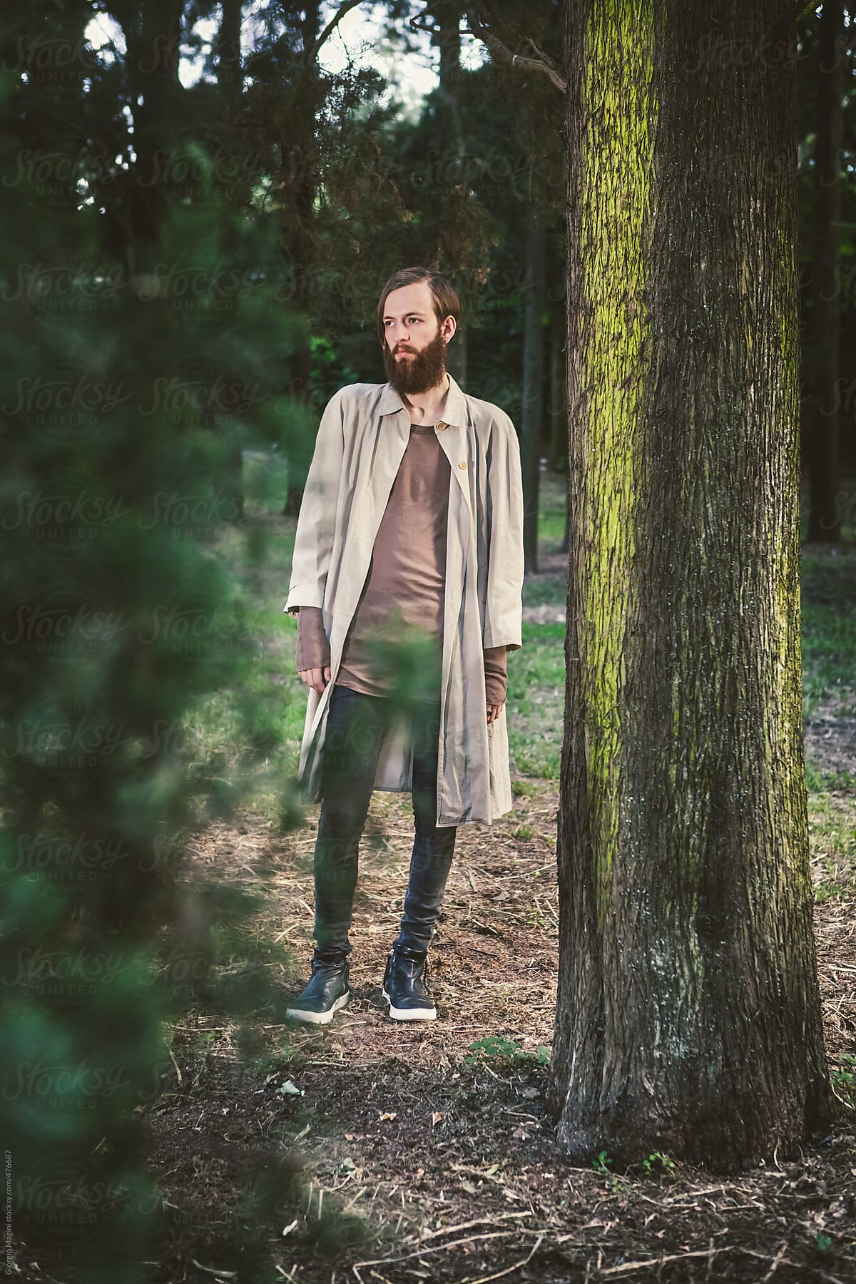 Bearded Young Man with Dark Fashion Clothes in the Woods