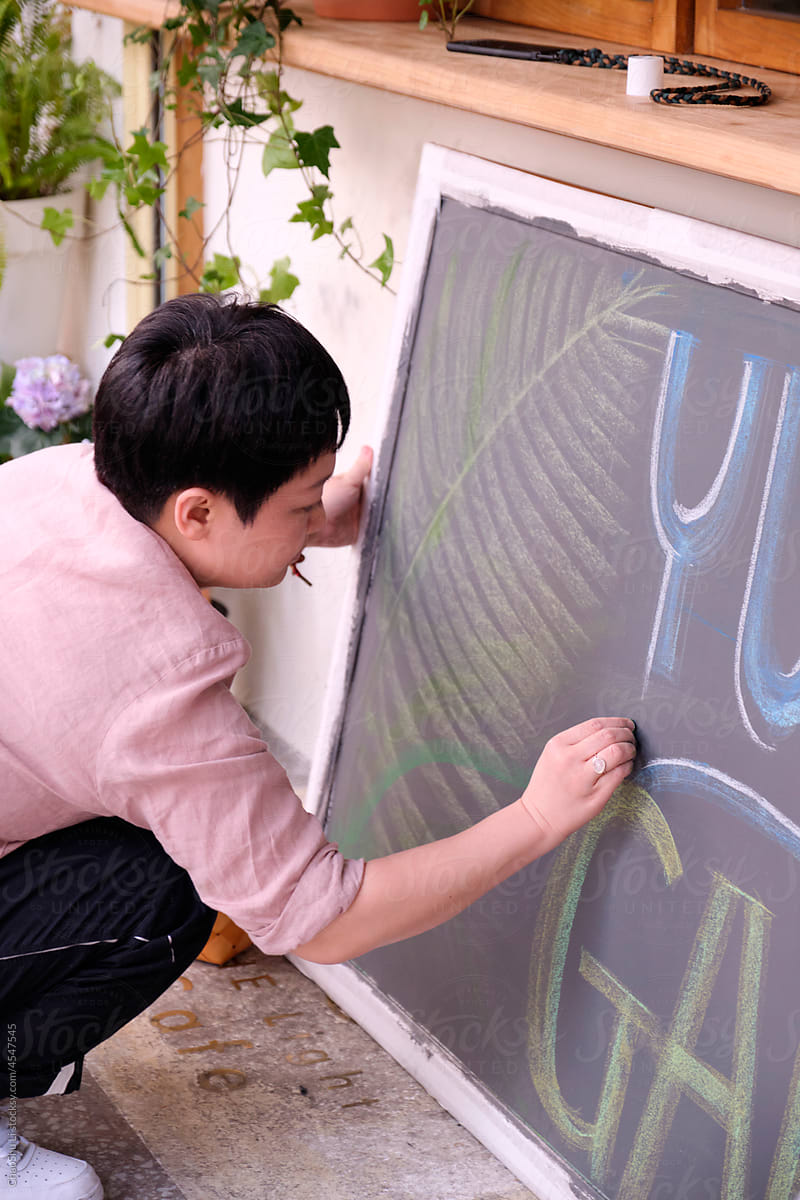 Closeup Asian woman creating chalk drawing on blackboard