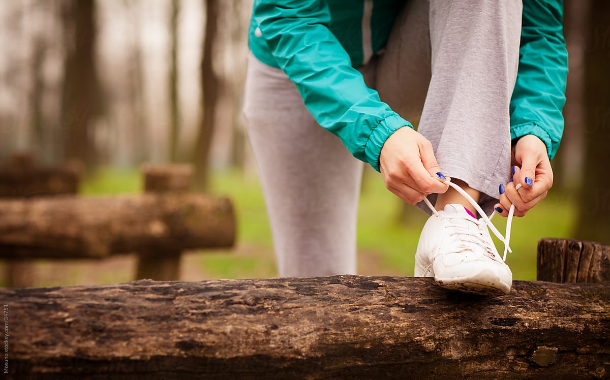 Young blond woman tying a shoe lace before jogging.