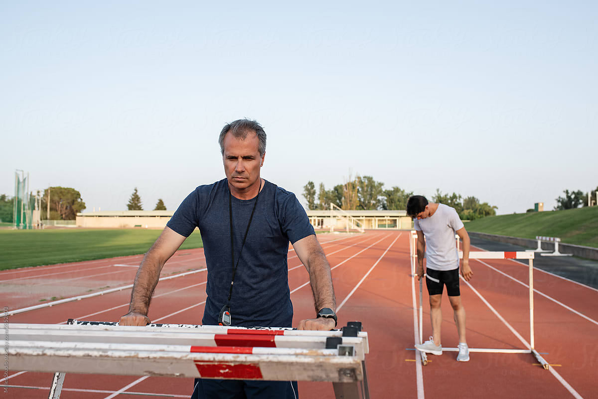 Instructor with athlete arranging hurdles during training