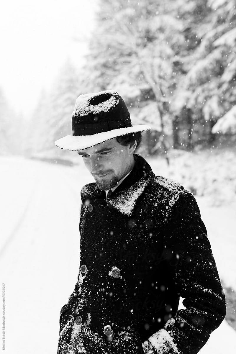 Man with a hat standing in snow