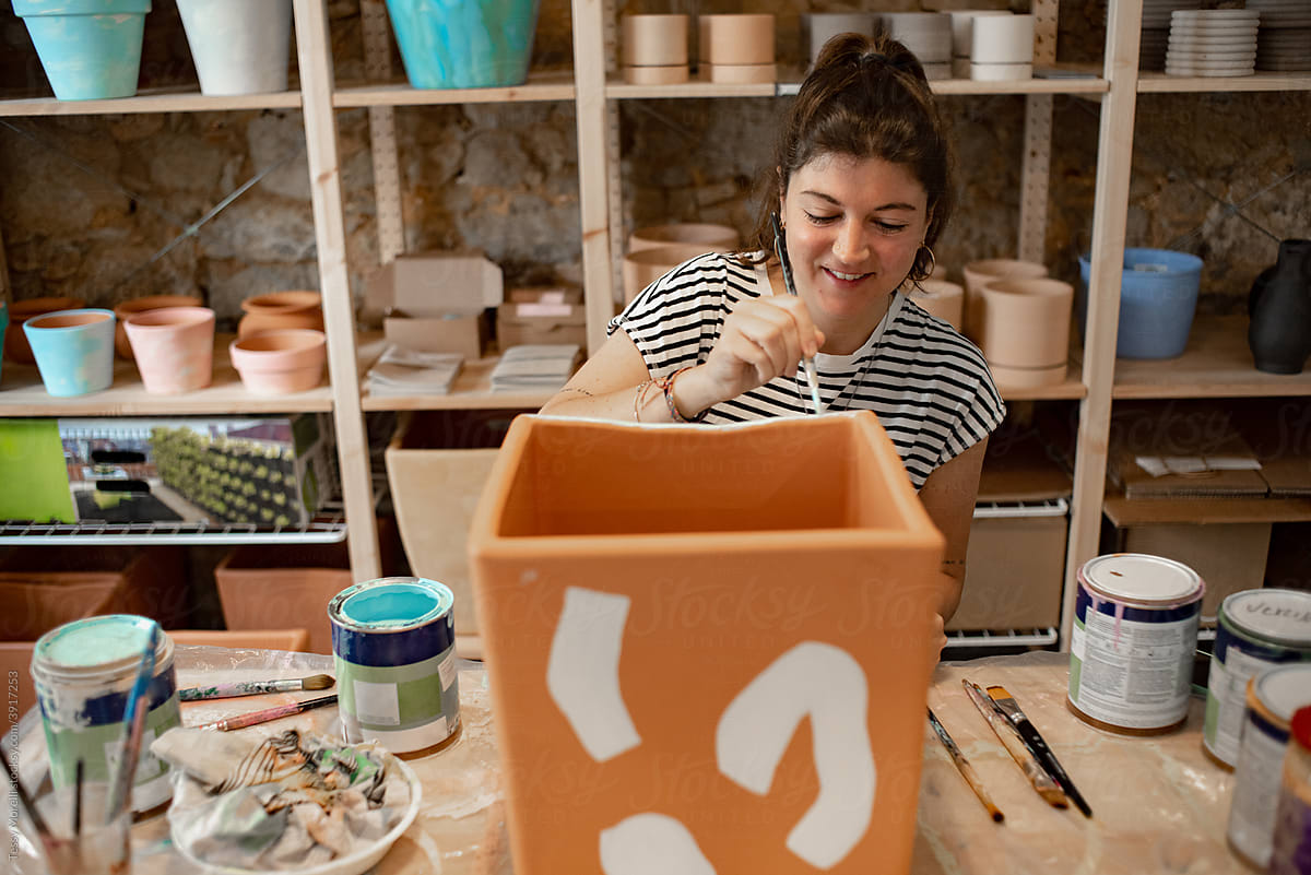 Happy woman painting a terracotta plant pot