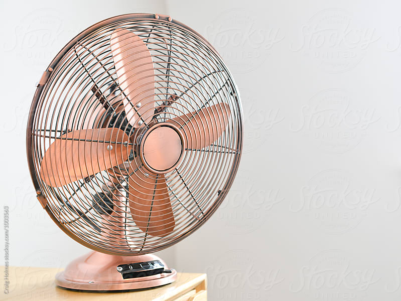 Rose gold colored traditional electric fan in a home.