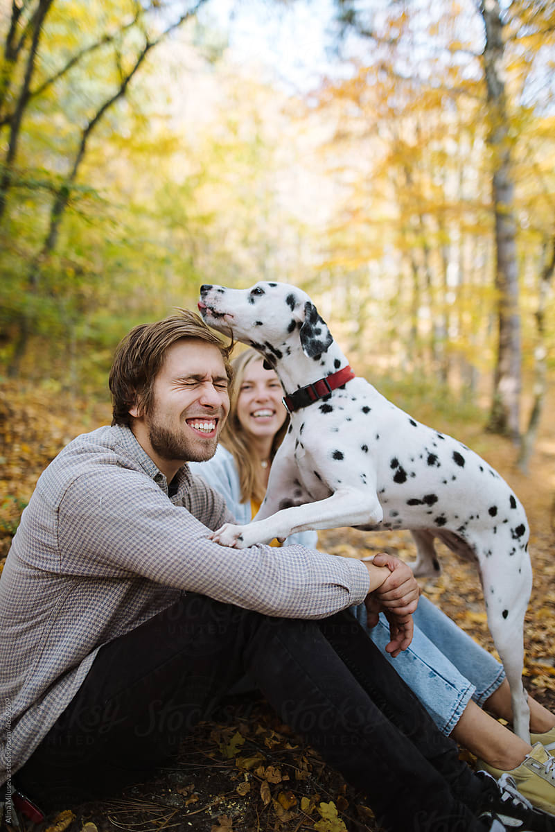 Happy couple having fun with their dog in autumn forest
