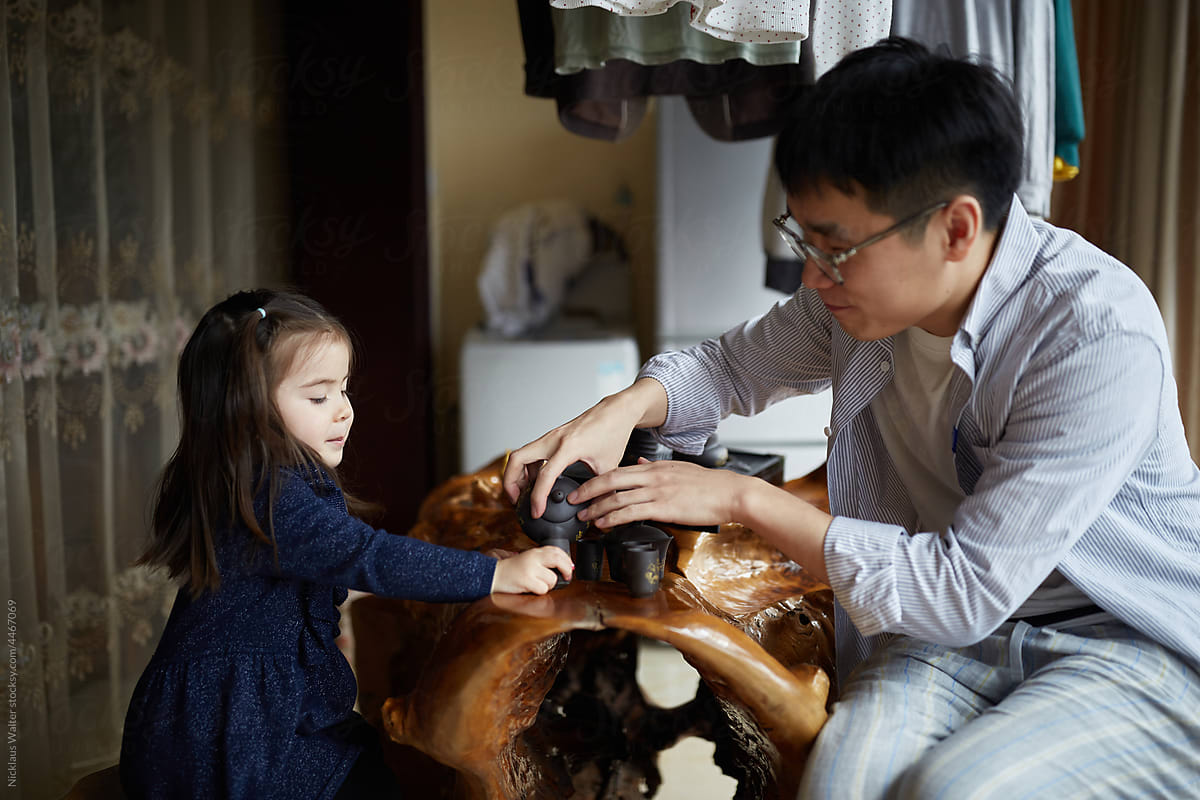 Chinese Father And Multiracial Daughter Play While Drinking Tea.