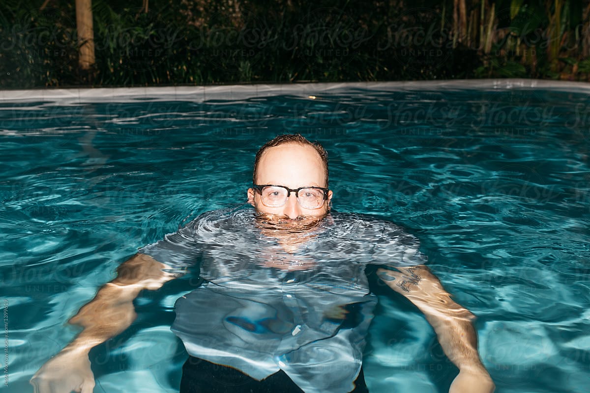 Young male wearing glasses and clothes in pool portrait underwater
