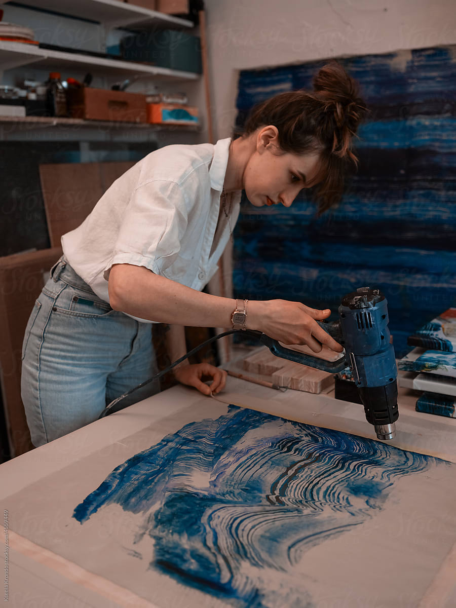 Young woman working with a construction hair dryer blue colours