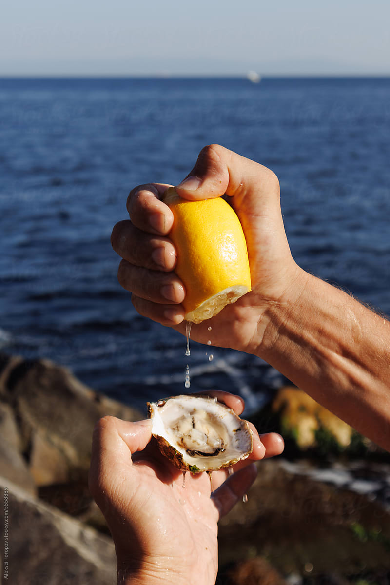 a man is watering an oyster with lemon juice