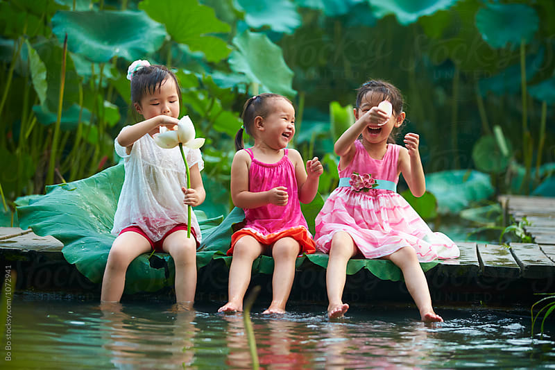 three little asian or CHinese girl playing water by the pond side