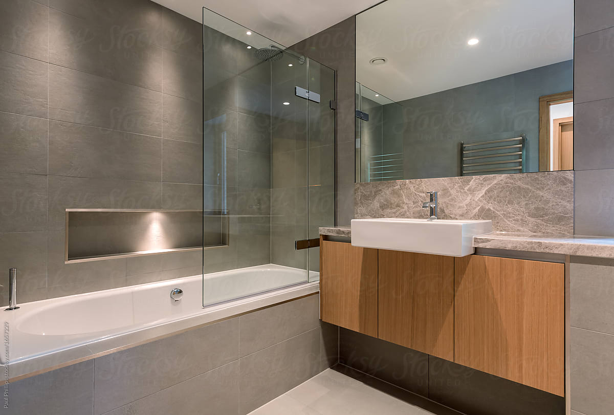 Contemporary bathroom with freestanding oval bathtub and shower behind.
