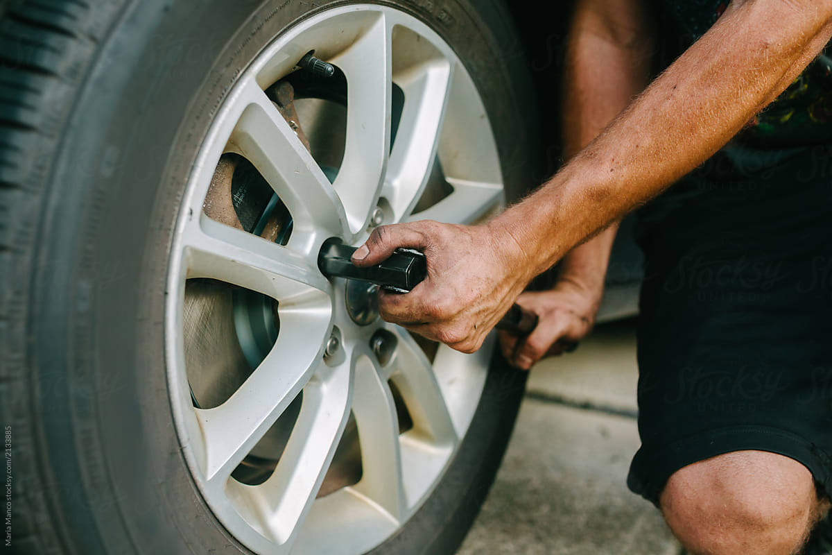 man changes tire on car