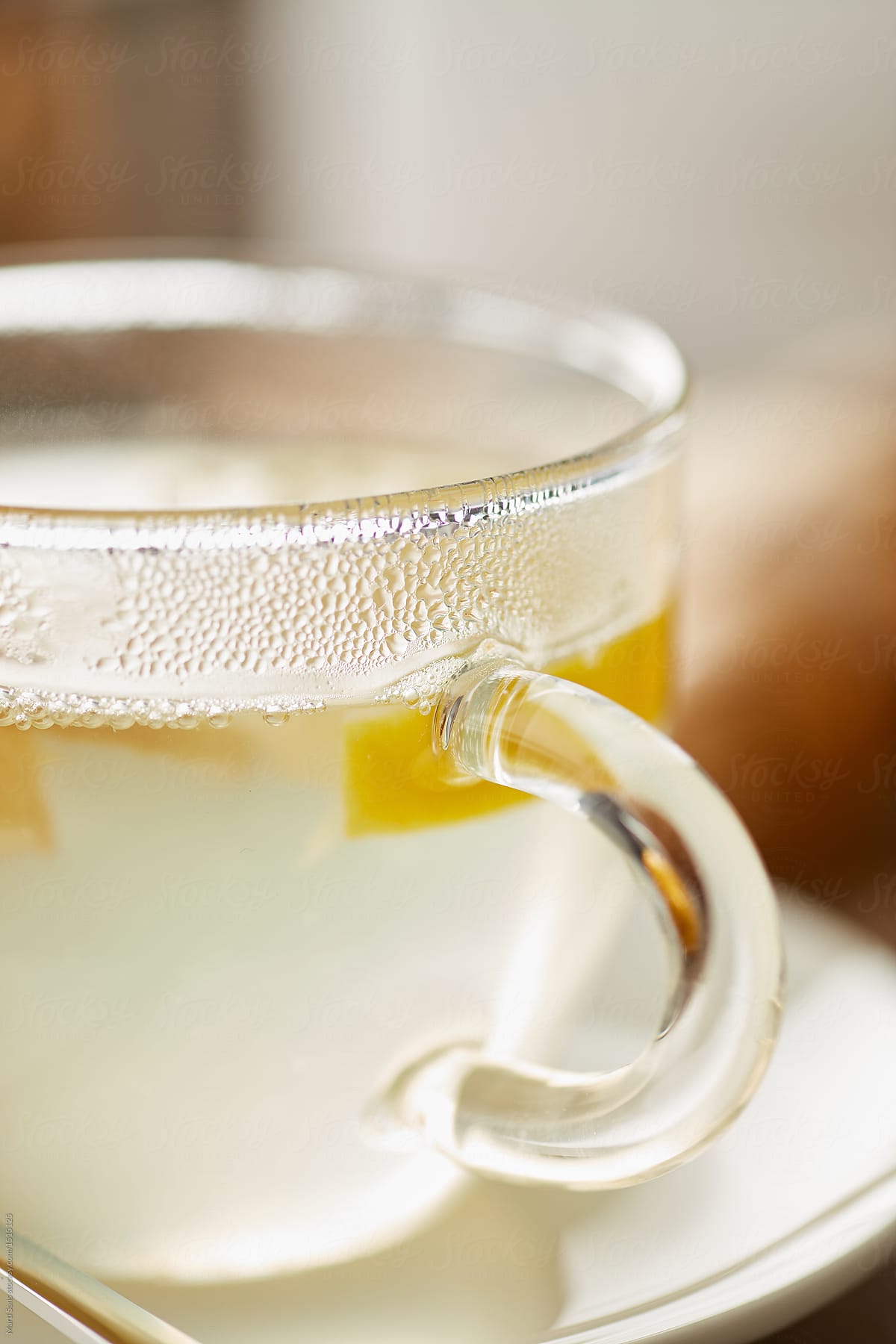 Transparent glass of tea with lemon, honey and ginger