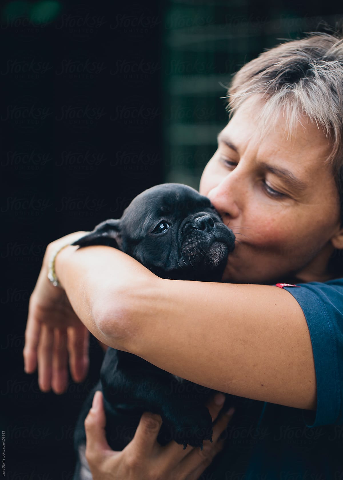 Woman holding in her arms and cuddling a French Bulldog puppy dog