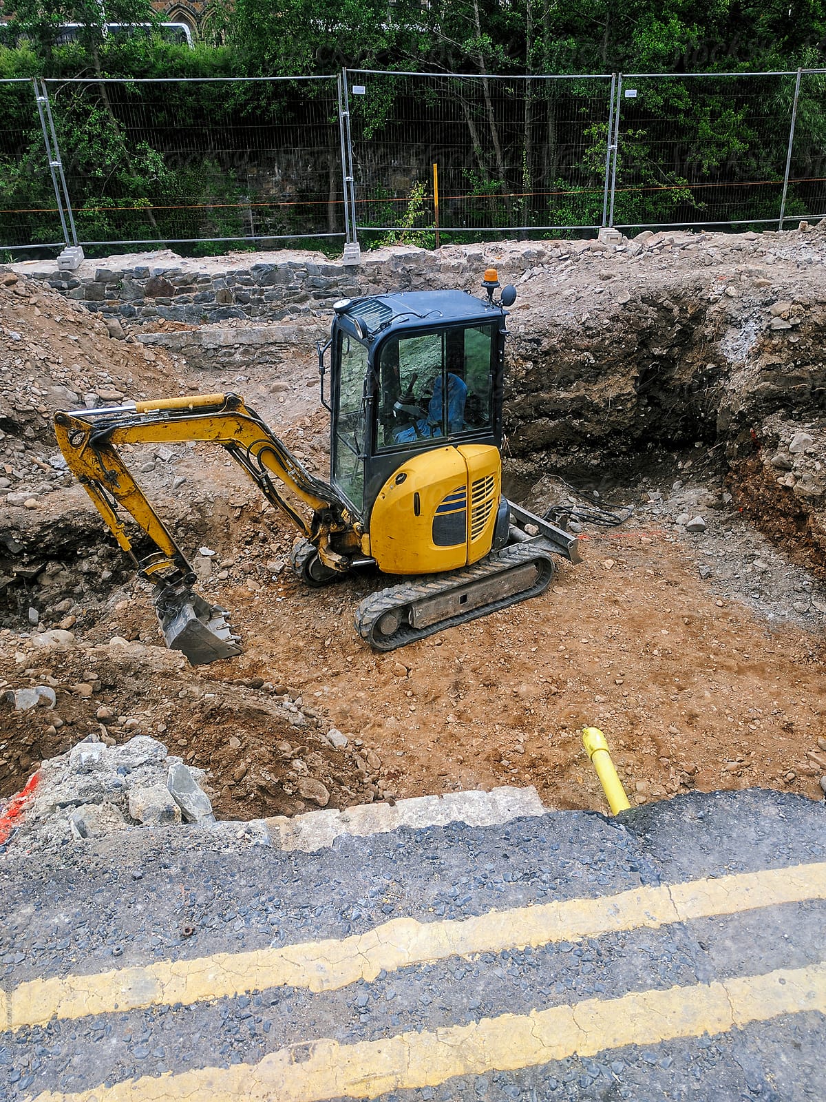 Mini excavator clearing ground on a building site for concrete foundations.