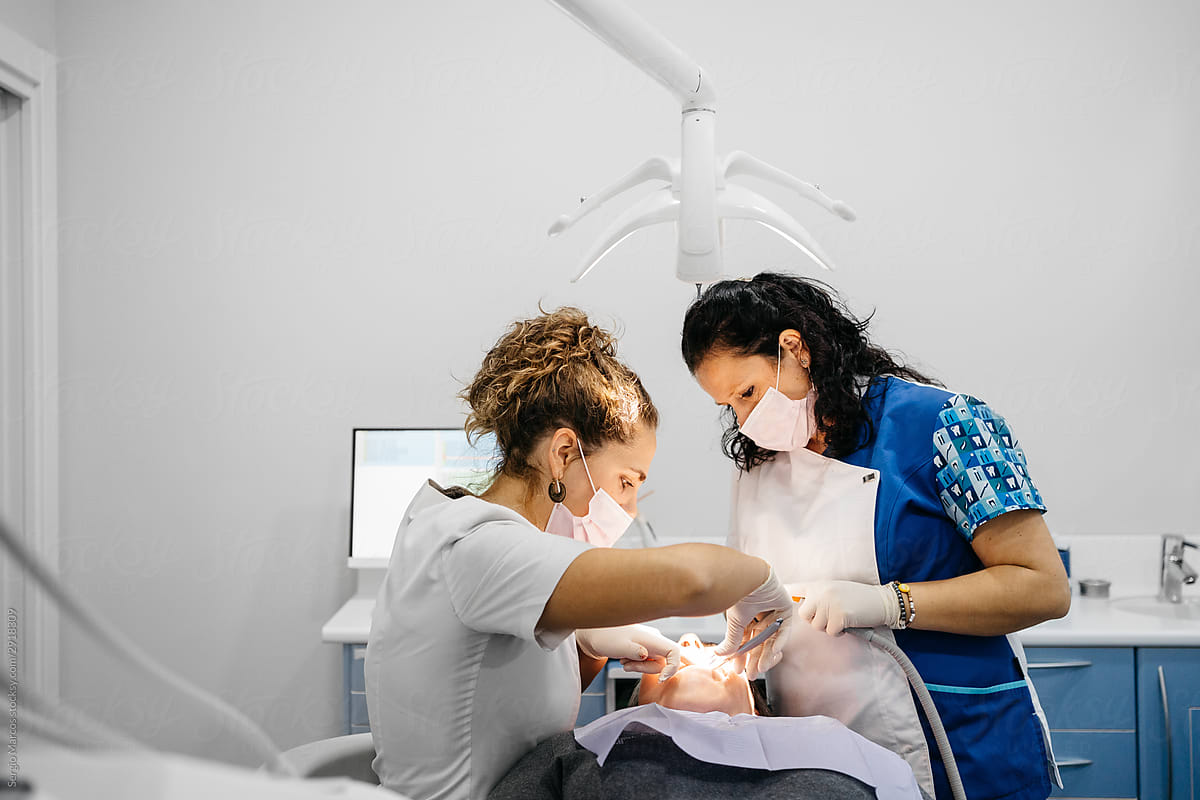 Orthodontist and assistant working with patient in dental office