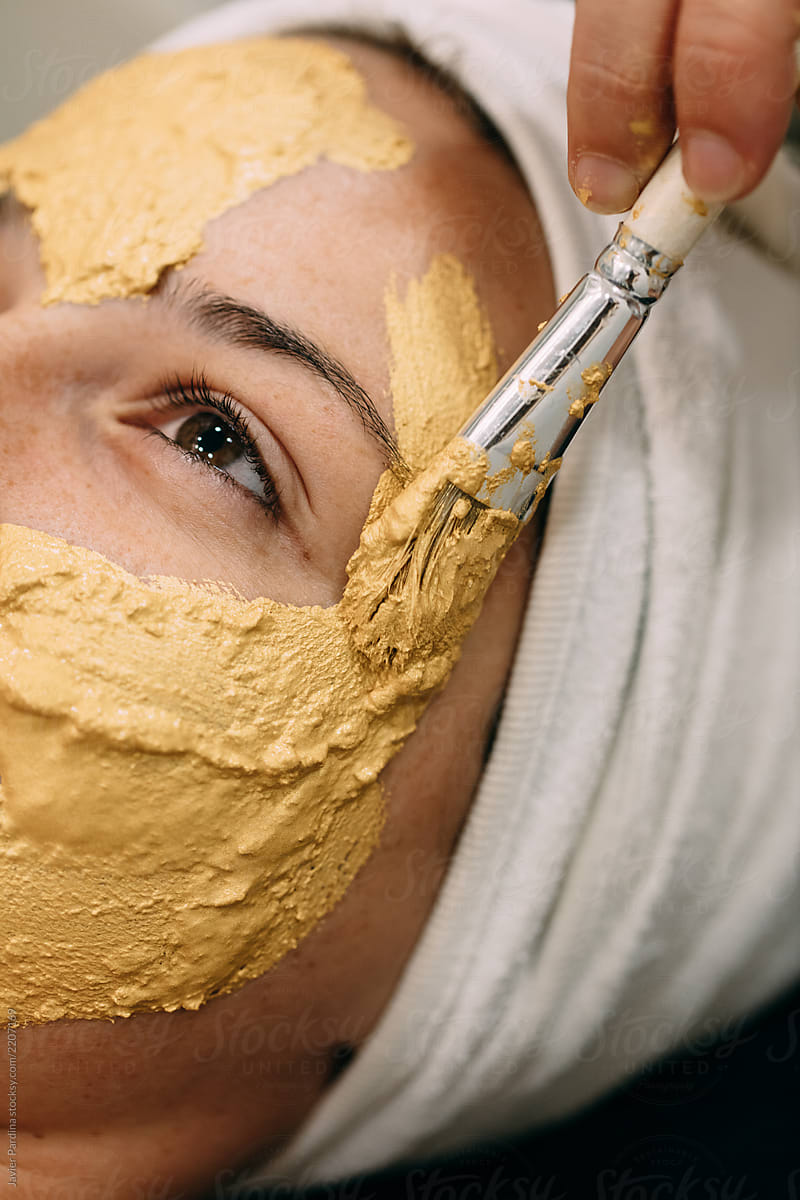 Woman applying gold mask at spa center