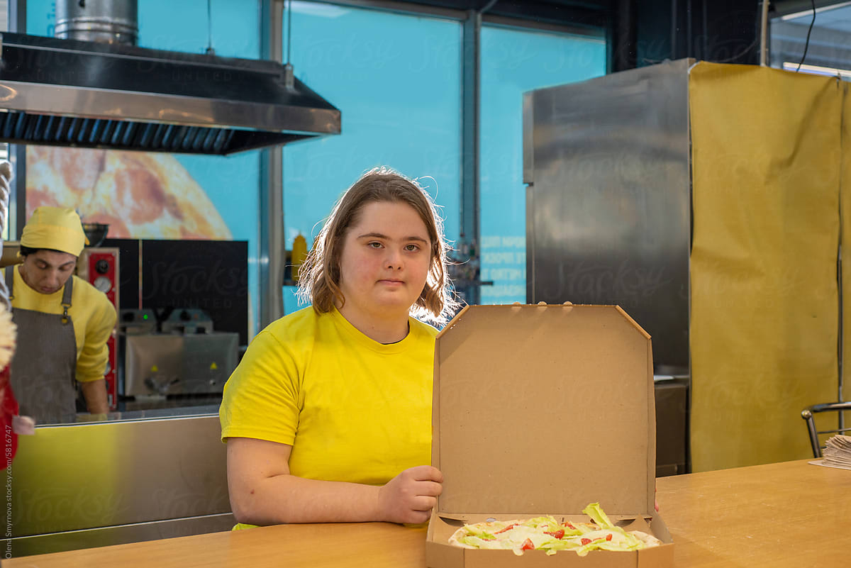Young woman with Down syndrome serves pizza in a pizzeria