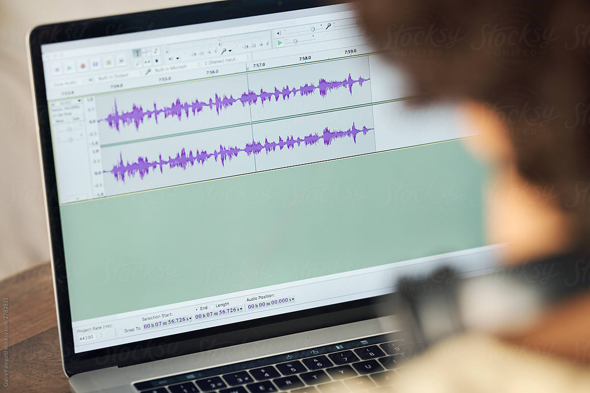 Podcaster editing audio files on laptop