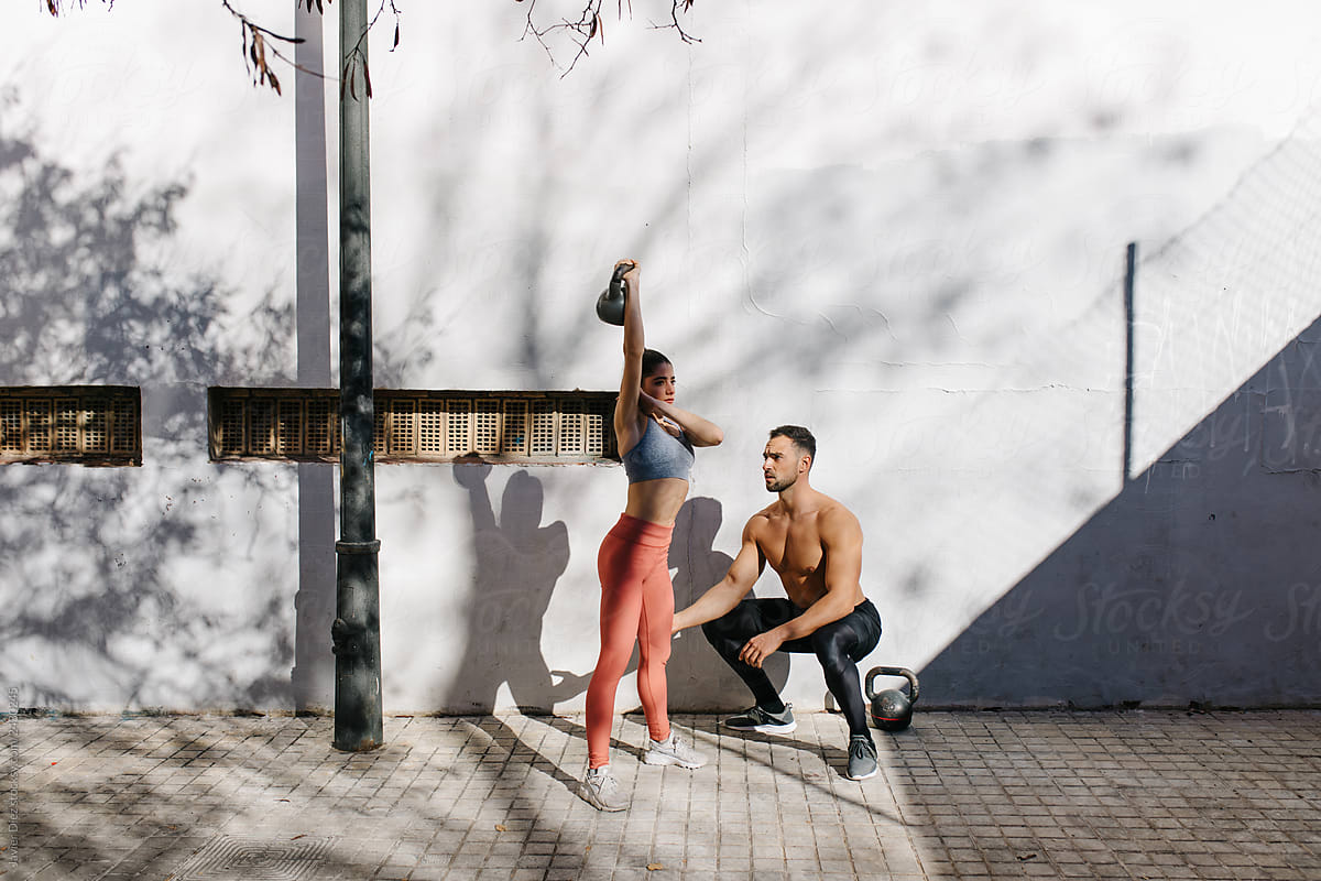 Young sportive man and woman doing workout near grey wall