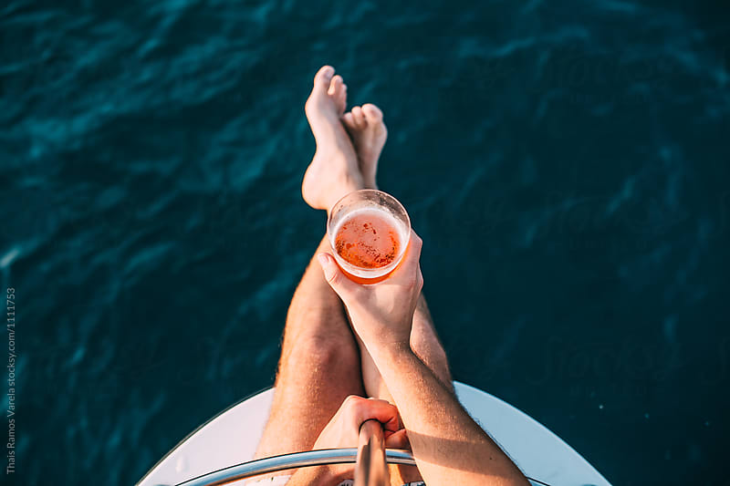 man holding a glass of beer sitting on a boat