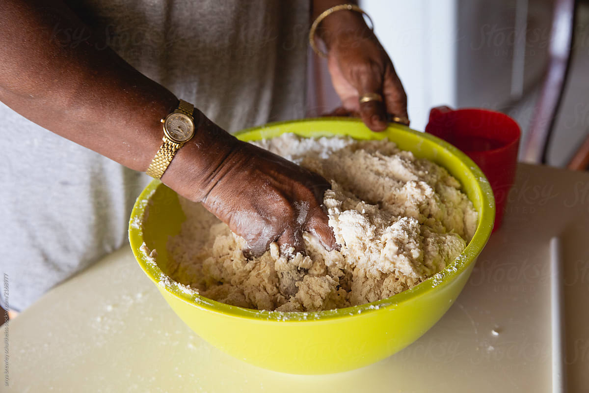 A pair of hands mixing dough in a bowl to make bread