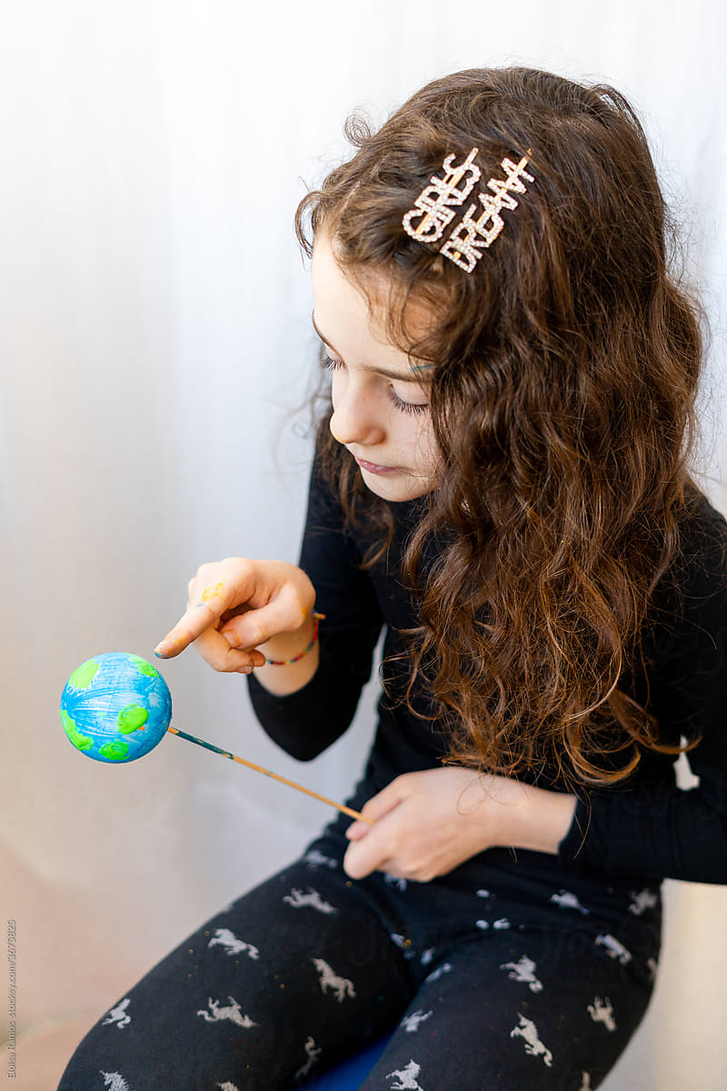 Young girl pointing to the planet earth with her finger