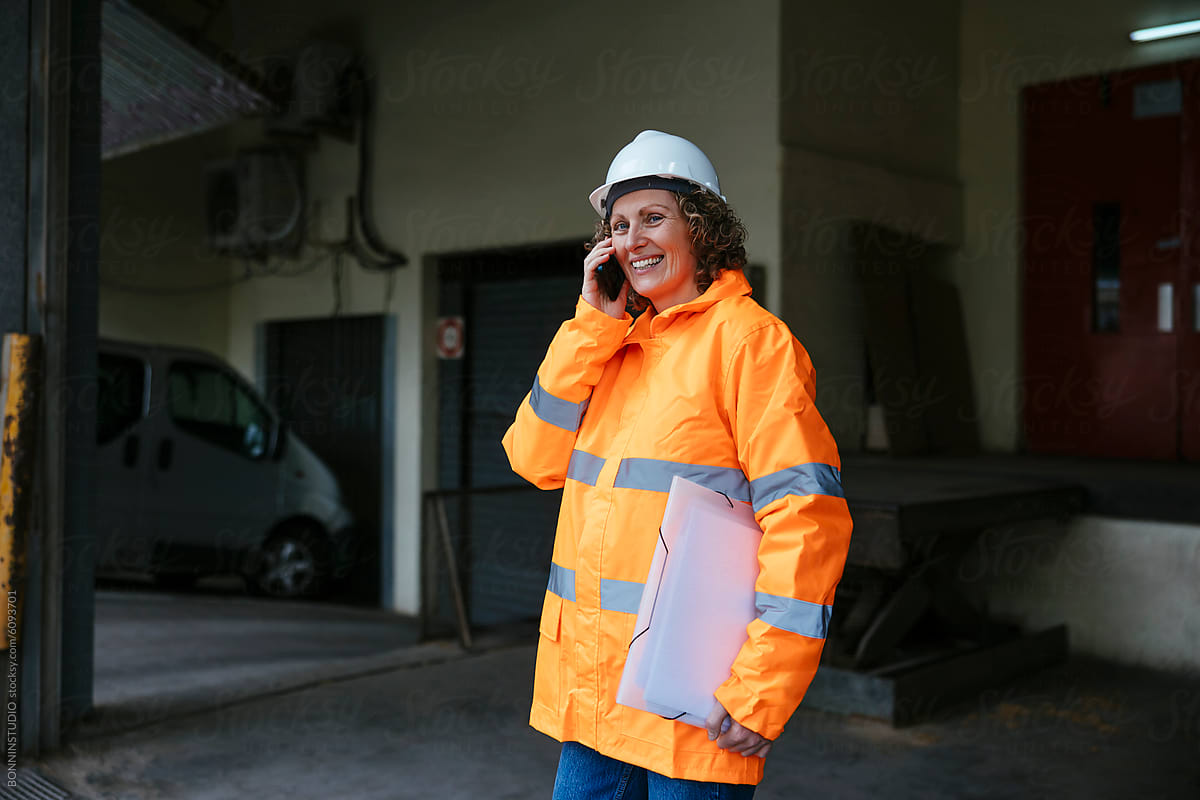 Female engineer in safety gear on phone at worksite