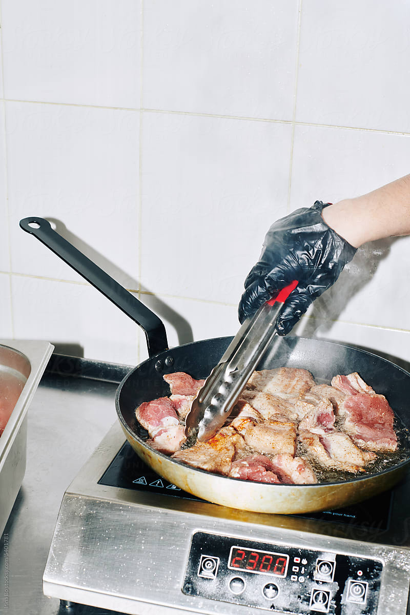 chef frying meat in a pan