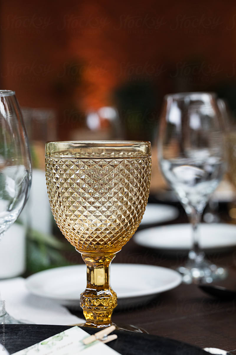 Closeup of a yellow wine glass on a wooden table