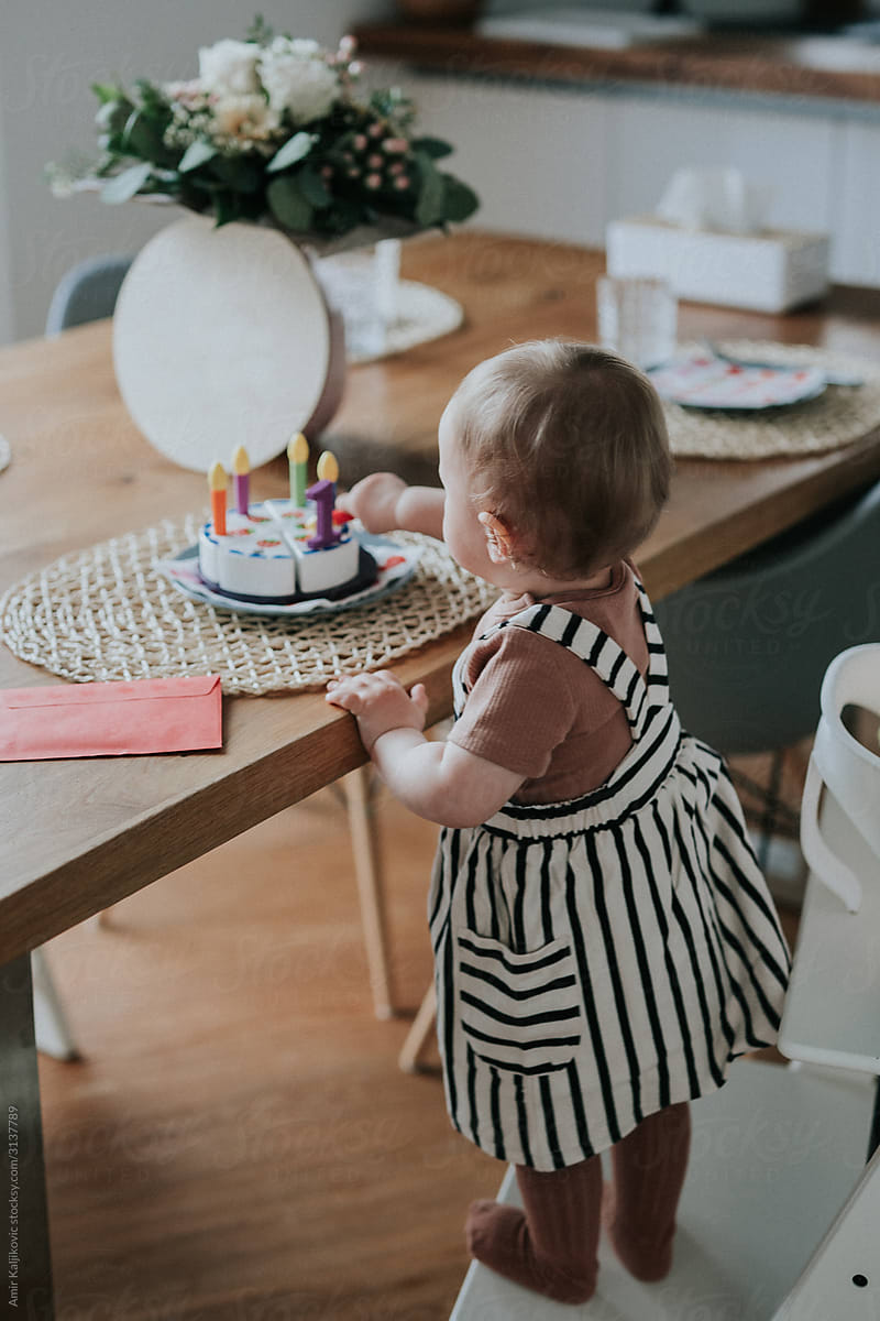 Little girl reaching for her birthday cake