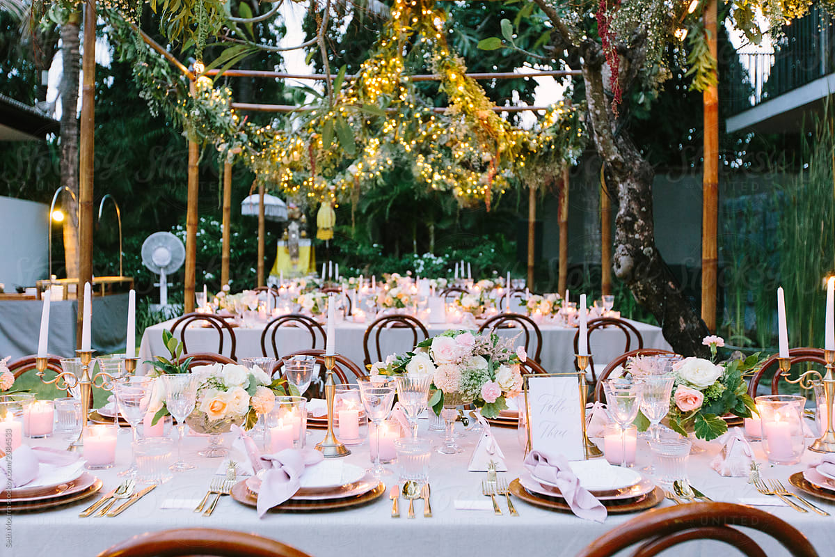 Outdoor, tropical wedding reception with hanging greenery garlands