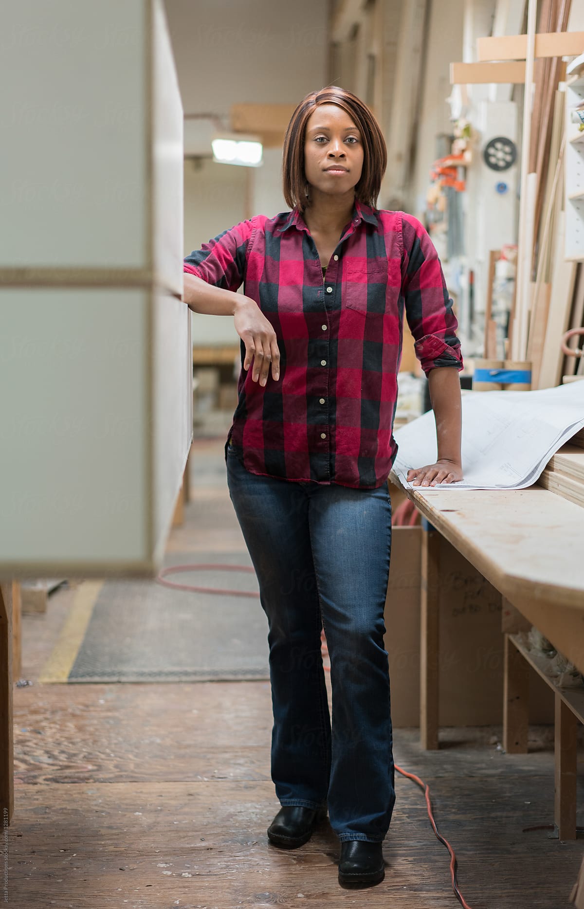 Vertical portrait of a black female woodworker in a small cabine