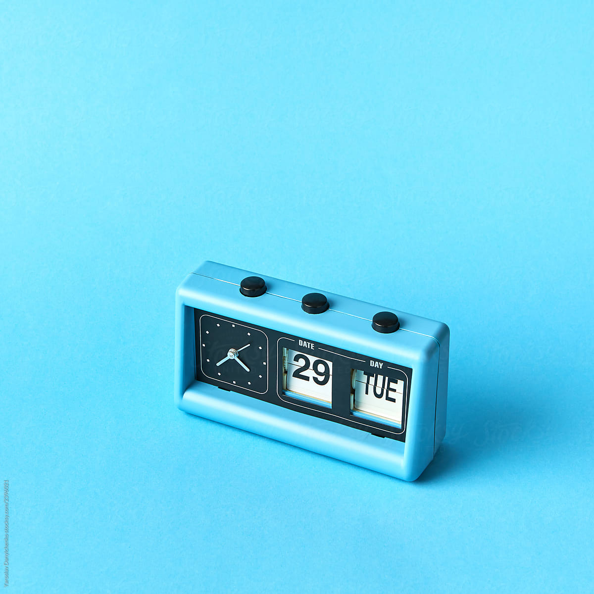 Vintage blue flip clock with calendar on a blue background with copy space. Day TUE, date 29, time is twenty two to five.