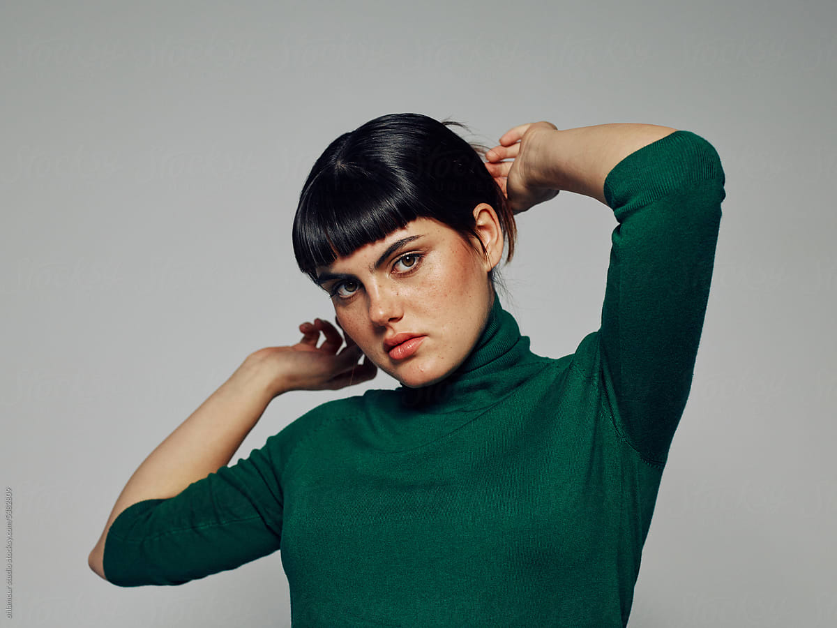 Confident model with green turtleneck fixing hair