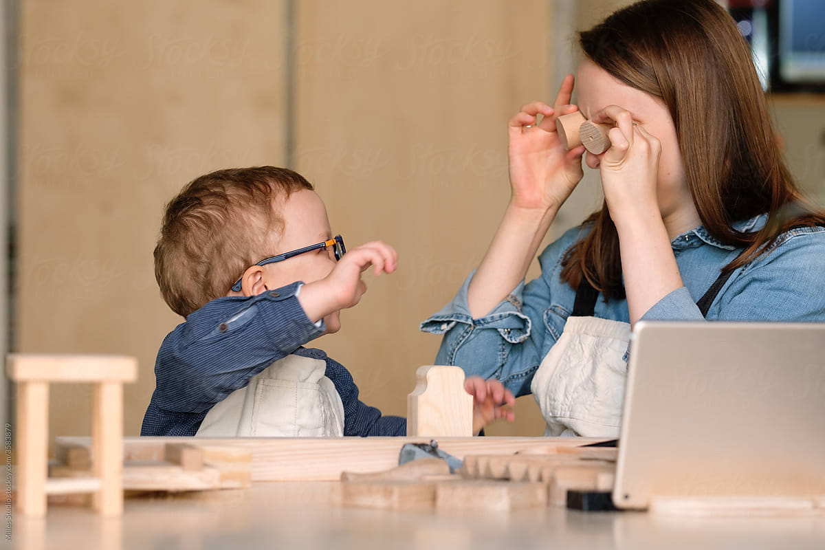 Mother and kid playing with wooden constructor