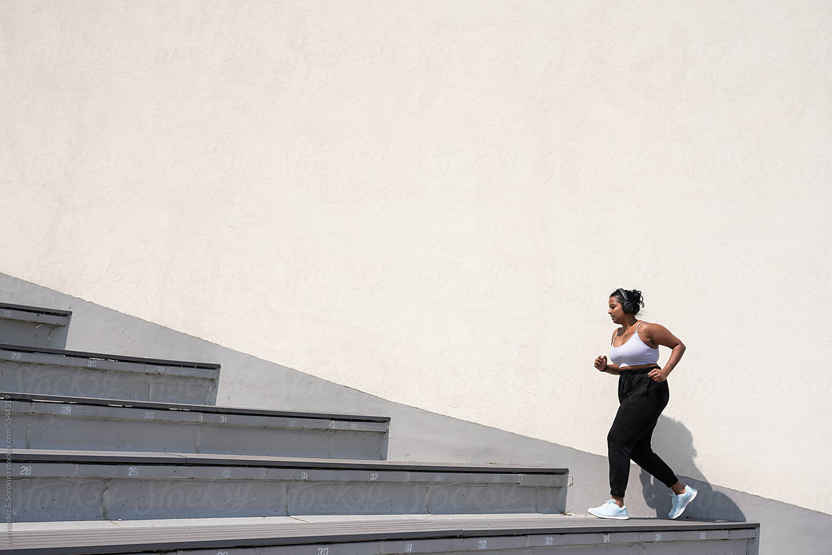 Curvy Woman Running Up The Stairs Outdoors At Sunny Day