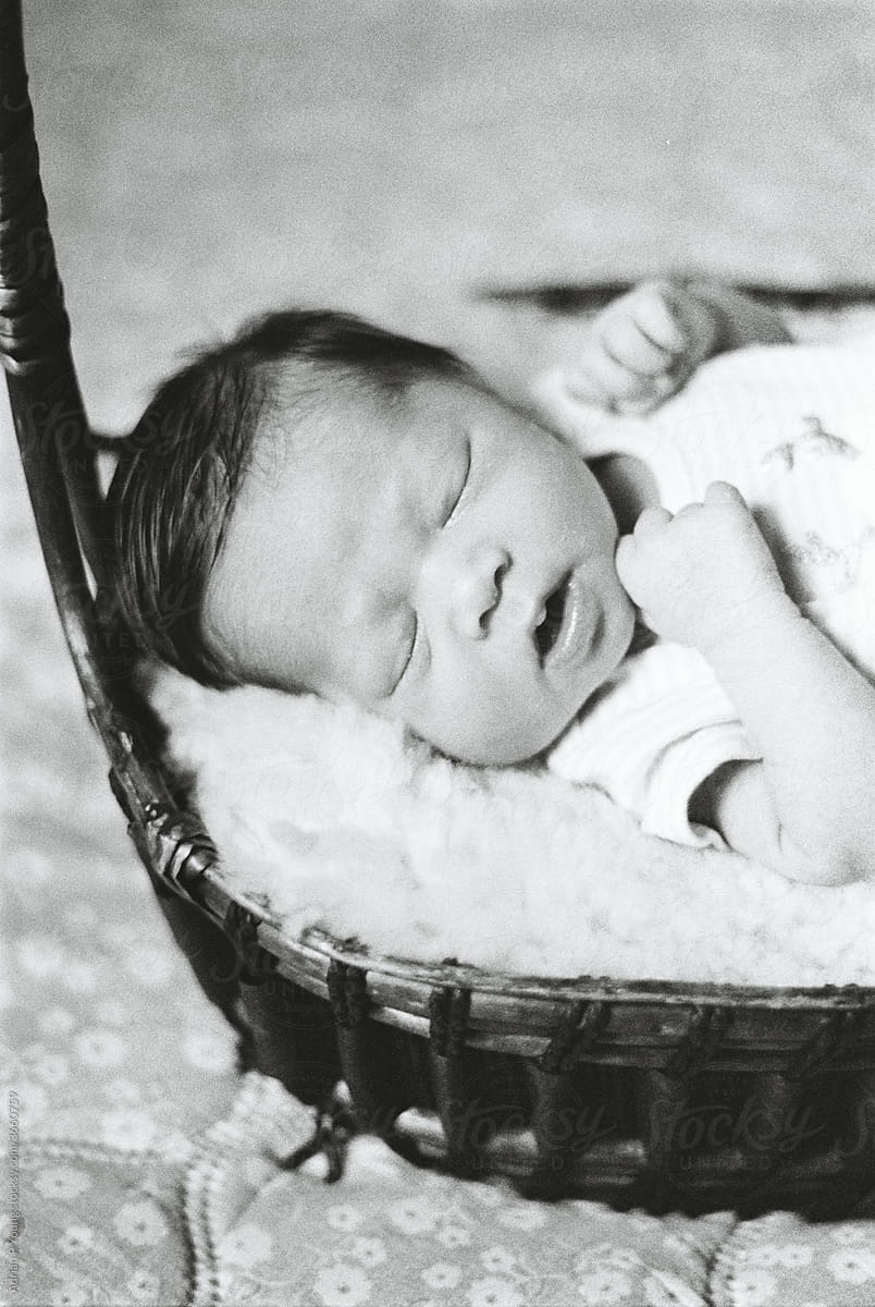Black and white film photo of a baby sleeping in a basket
