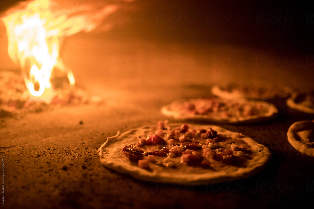 A traditionally made pizza baking in a wood fire oven